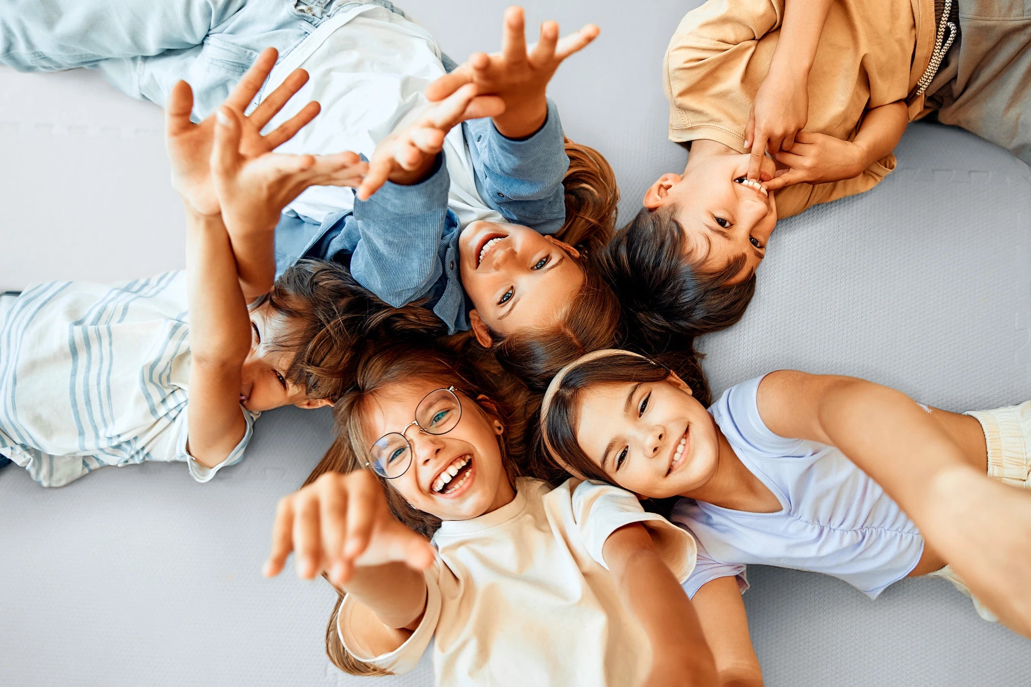 Smiling children lying on a large puzzle play mat