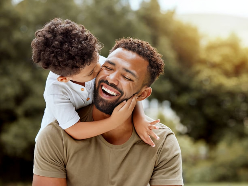 Father smiles as son kisses his cheek, showing their close bond