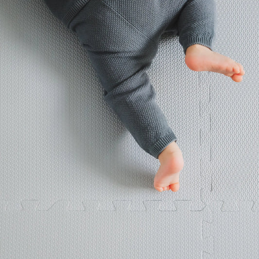 Toddler crawling on a textured kids foam puzzle play mat in angelic blue